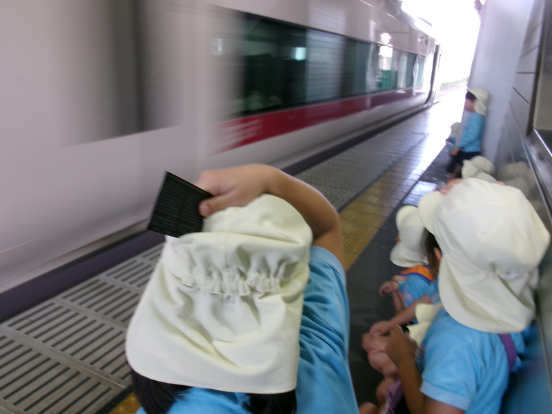 ホームで特急の通過を見学。「キャー」その速さに、思わず帽子を押さえていました。