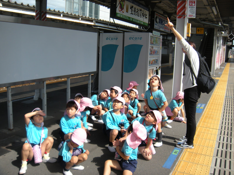 （案内板を見て）今から電車が来るよ。赤い字は「特急」で速い電車だよ。